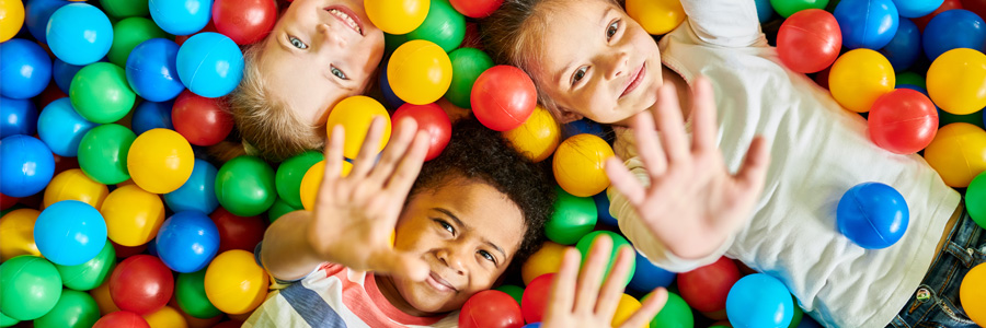 Three kids play in a colorful ball pit